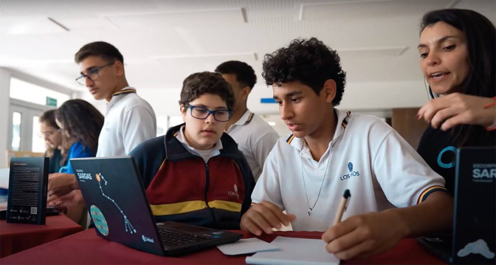 Adolescentes estudiando en un aula de clases frente a una computadora portátil